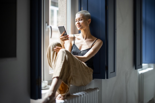 Mujer elegante hablando por teléfono en la ventana