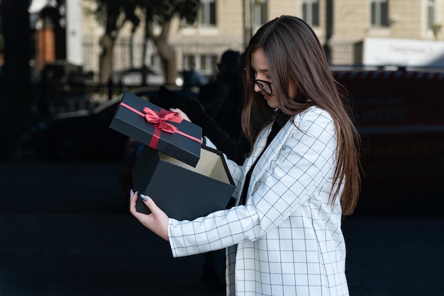 Mujer elegante con interés abrió caja de regalo negra. Hermosa mujer joven recibe regalo. Regalo de amado.