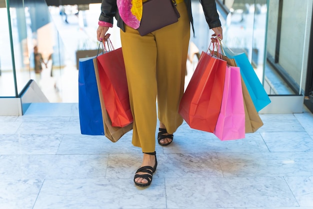 Foto mujer elegante irreconocible con bolsas de compras en el centro comercial antes de la venta de compras navideñas