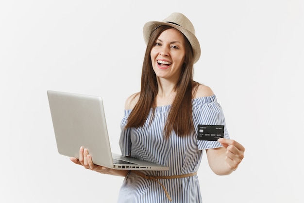 Mujer elegante joven que trabaja en la computadora portátil moderna de la PC, sosteniendo la tarjeta de crédito, dinero aislado en el fondo blanco. Finanzas, autónomos, negocios, concepto de compras en línea. Oficina móvil. Publicidad.