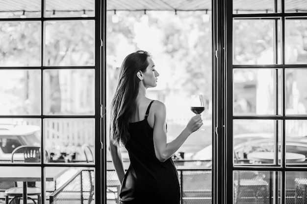 Mujer elegante joven sostenga una copa de vino tinto tiro interior enfoque selectivo
