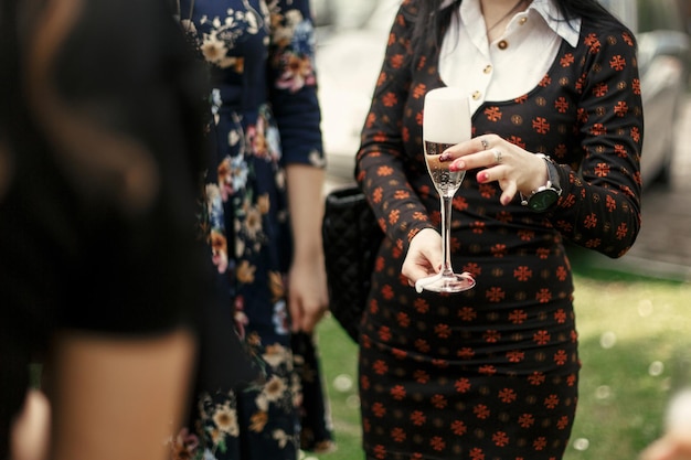 Mujer elegante de lujo sosteniendo una copa de champán y brindando en la celebración en la terraza del restaurante