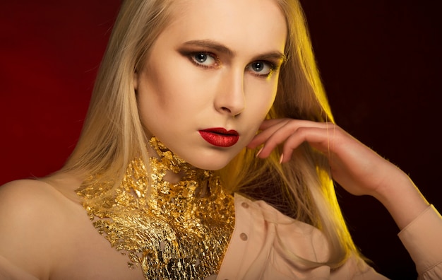 Mujer elegante con maquillaje brillante y lámina de oro en el cuello