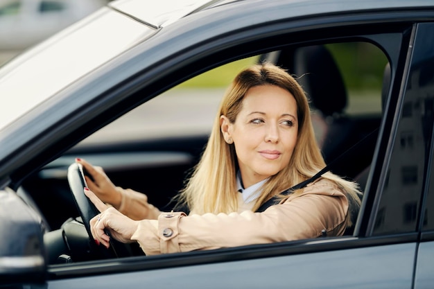 Una mujer elegante mira a través de la ventana mientras conduce un automóvil en una carretera