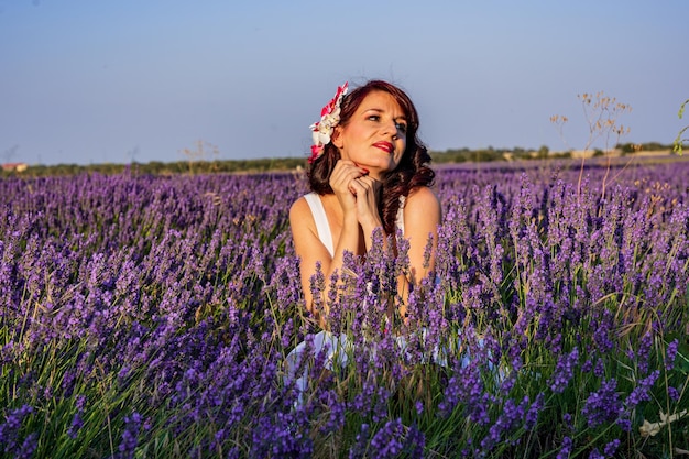 Mujer elegante mirando hacia otro lado mientras posa al aire libre en un colorido campo de lavanda