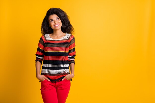 Mujer elegante con peinado afro posando contra la pared naranja