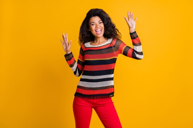 Mujer elegante con peinado afro posando contra la pared naranja