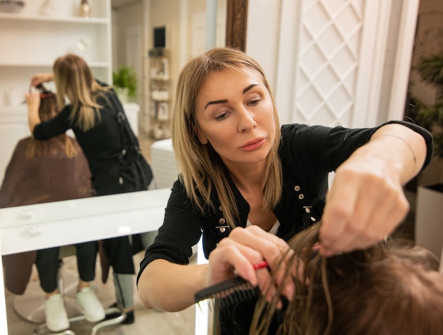 Mujer elegante peluquería madura cortando el cabello del cliente en salón de belleza. Concepto de belleza