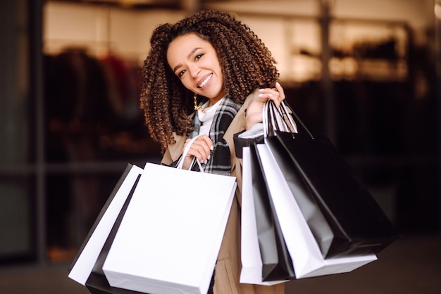 Mujer elegante en ropa de moda con bolsas de compras cerca del centro comercial. Mujer después de ir de compras.