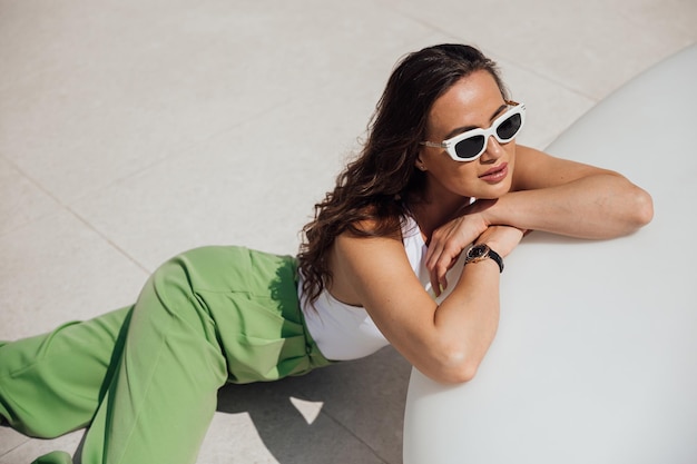 Mujer elegante y segura de moda con gafas de sol rosas de moda, pañuelo en la cabeza, chaqueta de traje con bolsa verde posando en la calle de la ciudad europea Retrato de moda al aire libre Copiar espacio vacío para texto