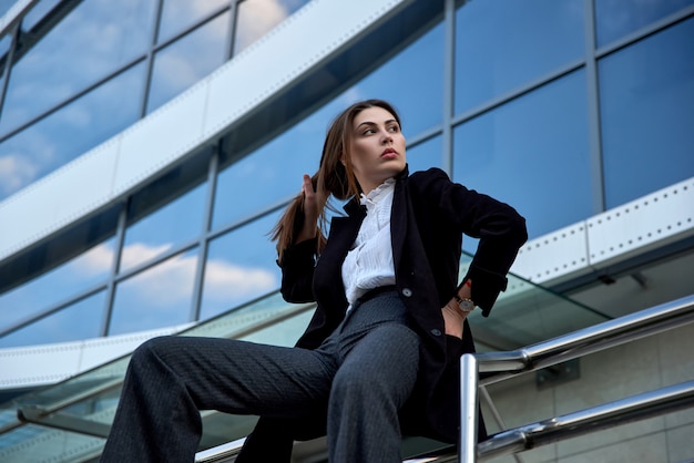 Foto mujer elegante se sienta en la barandilla de la calle