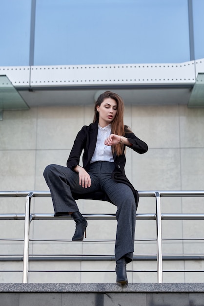 mujer elegante se sienta en la barandilla de la calle