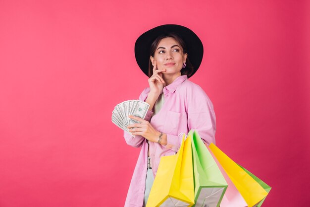 Mujer elegante con sombrero en la pared roja rosa