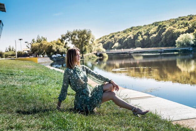 Mujer elegante en vestido de moda se encuentra cerca del lago