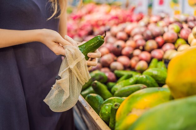 Mujer elige aguacate en un supermercado sin usar una bolsa de plástico reutilizable para comprar