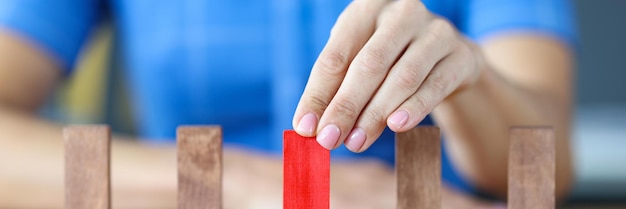 La mujer elige uno de los bloques de madera roja de muchos bloques de madera beige en fila eligiendo una idea de persona