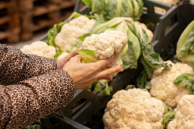 Mujer elige una coliflor en el supermercado