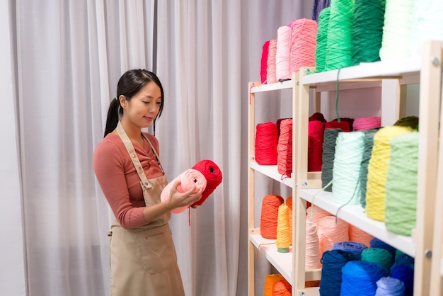 La mujer elige el color del hilo para hacer la alfombra de tufting en el estudio