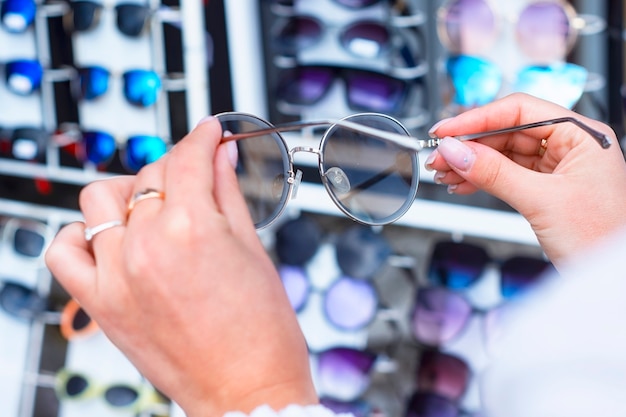 Una mujer elige gafas de sol protectoras en el contexto de una vitrina con gafas.