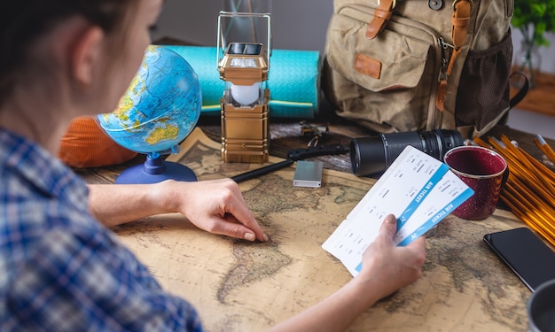 Foto una mujer elige un lugar para su próximo viaje señalando un mapa del mundo en una mesa de madera con equipo de campamento.