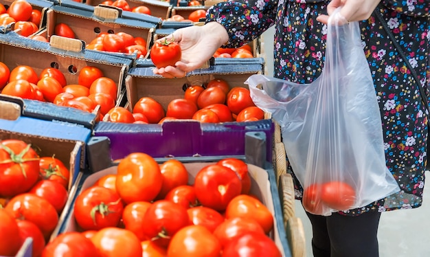 Una mujer elige tomates en un supermercado. Enfoque selectivo. Comida.