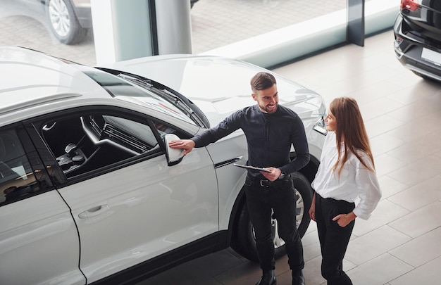 Mujer eligiendo auto con la ayuda de un asistente masculino en el interior del salón.