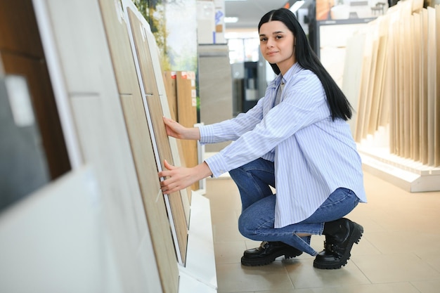 Mujer eligiendo azulejos del baño en el mercado de la construcción