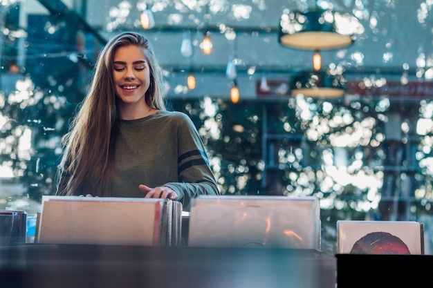 Mujer eligiendo disco de vinilo en la tienda de discos de música