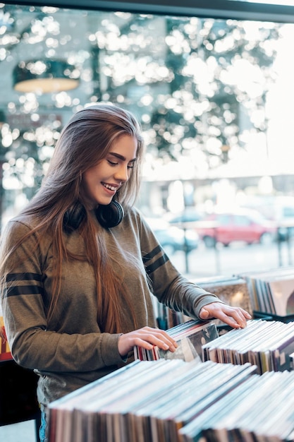 Mujer eligiendo disco de vinilo en la tienda de discos de música