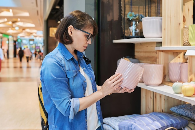 Mujer eligiendo macetas decorativas de flores en una tienda de decoración casera moderna