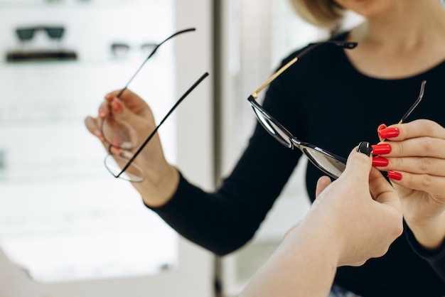 Mujer eligiendo un par de anteojos en la tienda de óptica