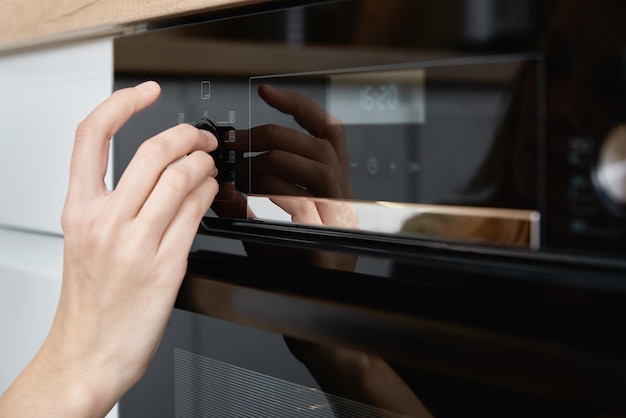 Mujer eligiendo programa en panel de horno eléctrico