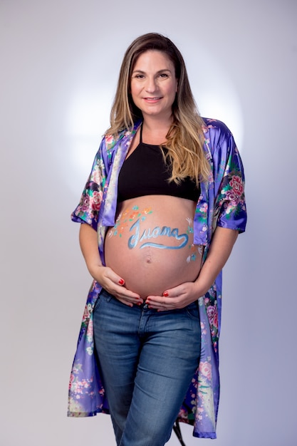 Mujer embarazada acariciando su barriga que tiene escrito el nombre de Juana