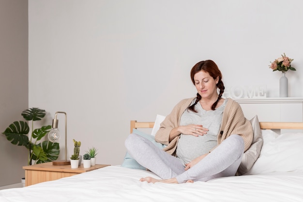 Foto mujer embarazada de alto ángulo en la cama