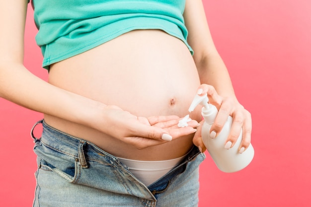 Mujer embarazada aplicando crema contra las estrías