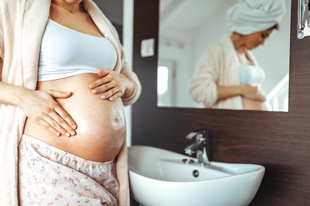 Mujer embarazada aplicando crema para estirar el estómago