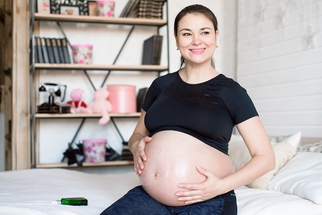 Mujer embarazada aplicando crema en el vientre. Crema de embarazo en el vientre de una mujer embarazada.