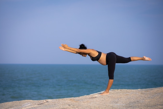 Mujer embarazada asiática yoga en la playa atardecer verano