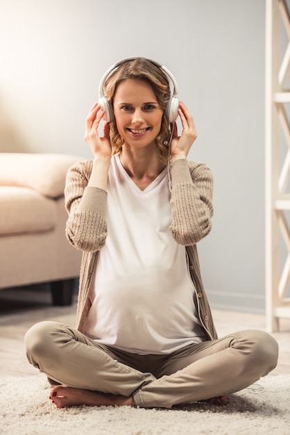 Mujer embarazada en auriculares está escuchando música.