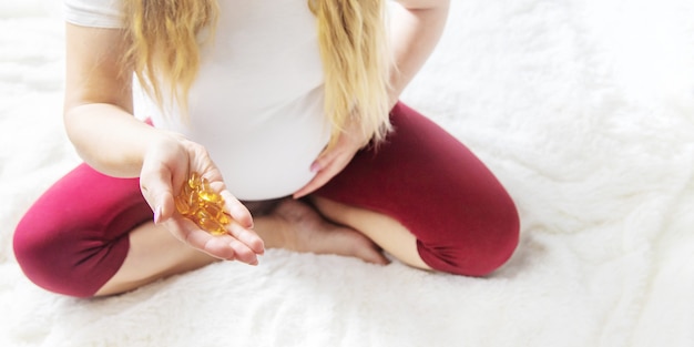 Una mujer embarazada bebe omega tres vitaminas. Enfoque selectivo.