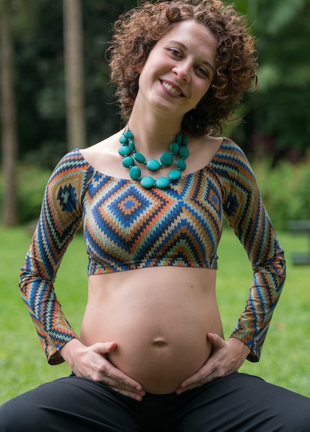 Mujer embarazada brasileña tocando su vientre posando para la cámara.