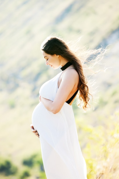 Mujer embarazada con cabello largo sano al aire libre