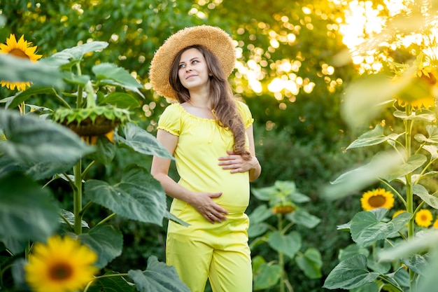 Una mujer embarazada camina en un campo con girasoles.