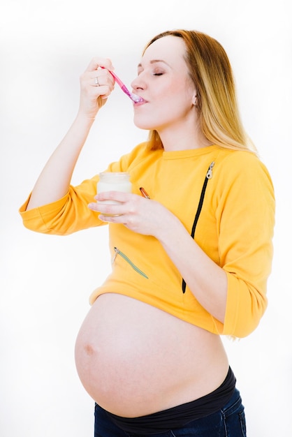 Mujer embarazada caucásica con vaso de yogur aislado en blanco