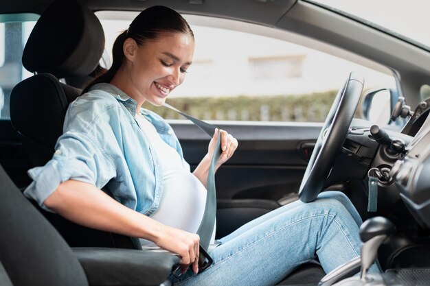 Foto mujer embarazada en el coche ajustando el cinturón de seguridad para la seguridad en el interior