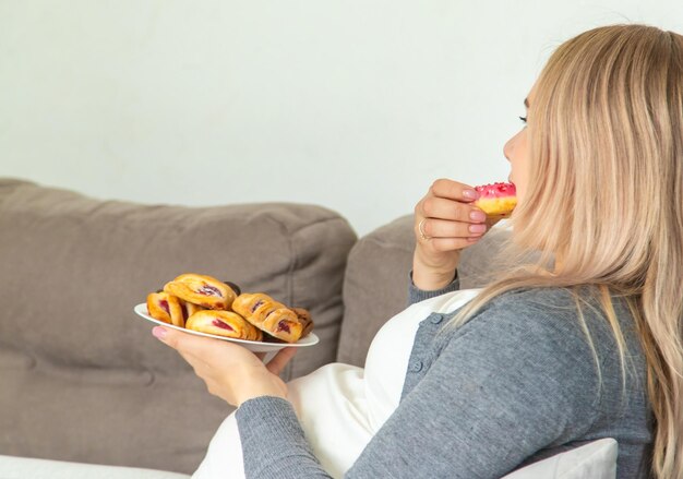 Una mujer embarazada come un donut dulce Enfoque selectivo