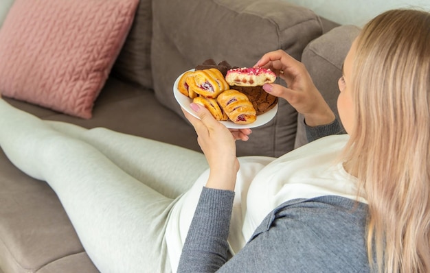 Una mujer embarazada come un donut dulce Enfoque selectivo