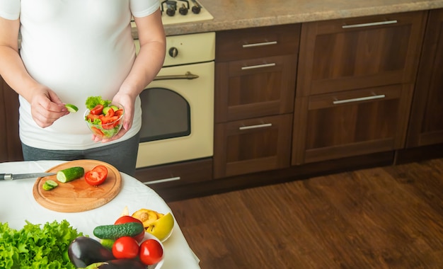 Una mujer embarazada come vegetales y frutas.