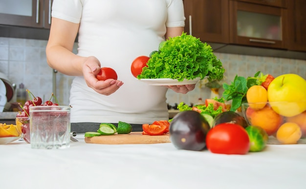 Una mujer embarazada come vegetales y frutas.