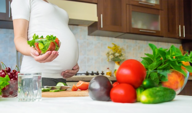 Una mujer embarazada come vegetales y frutas.